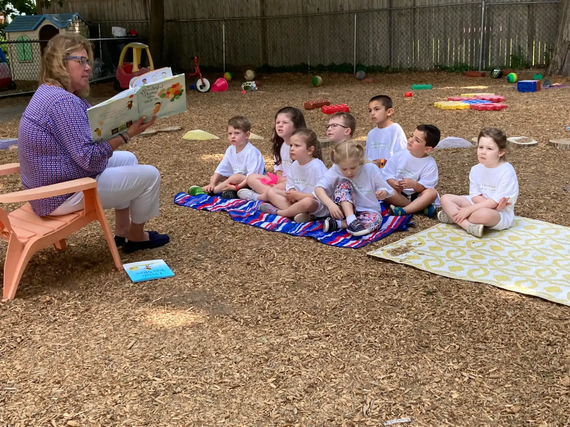 a group of children sitting on a blanket on a blanket in the sand