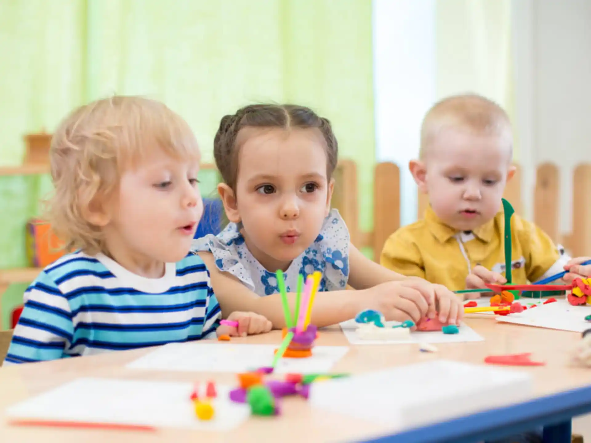 a group of children sitting at a table with colored pencils