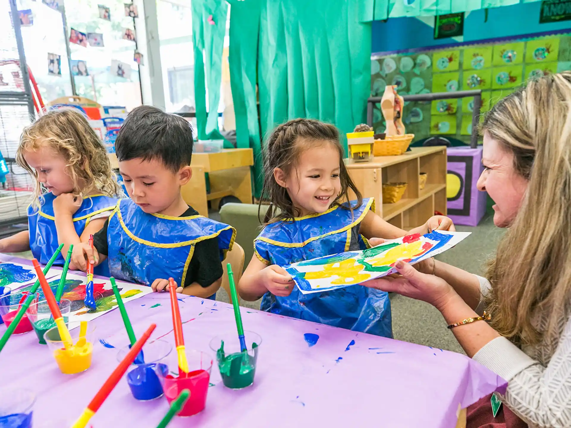 a person and kids sitting at a table with colored markers