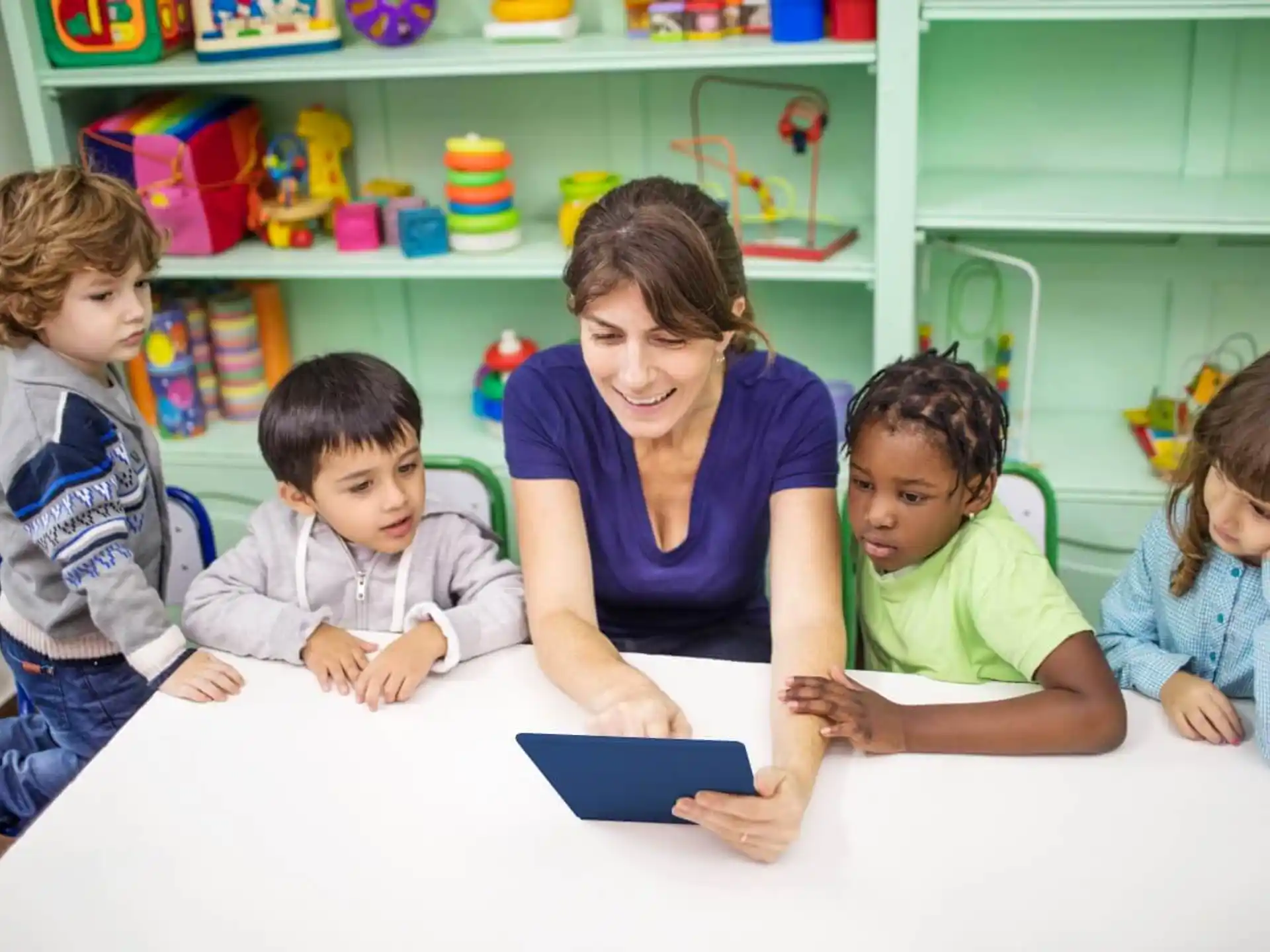 a person and several children looking at a tablet