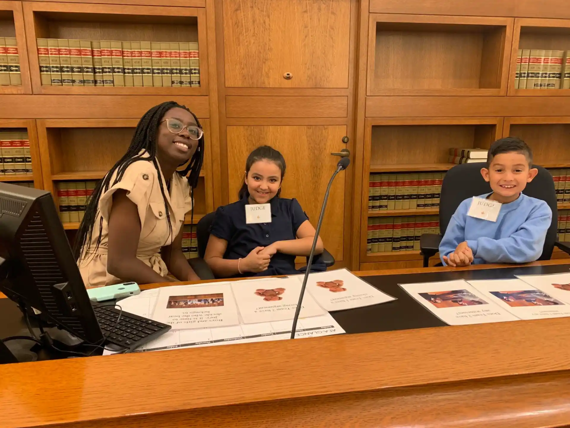 a group of people sitting at a table with a laptop and papers