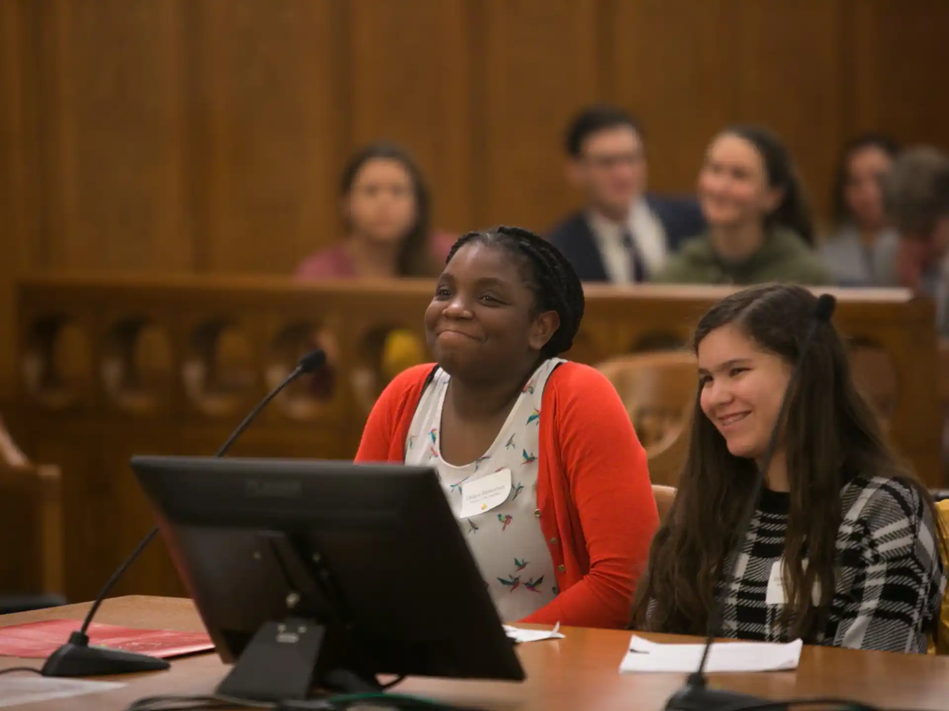 a woman and a man sitting at a desk with a laptop