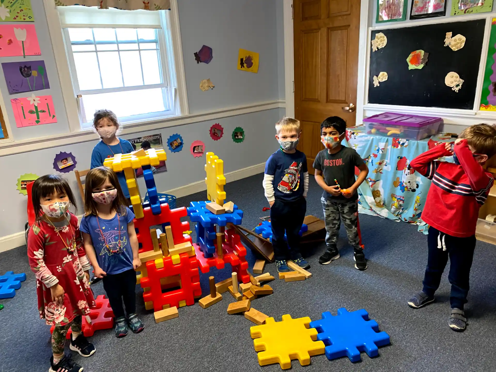 a group of children playing on a blue and yellow toy in a room