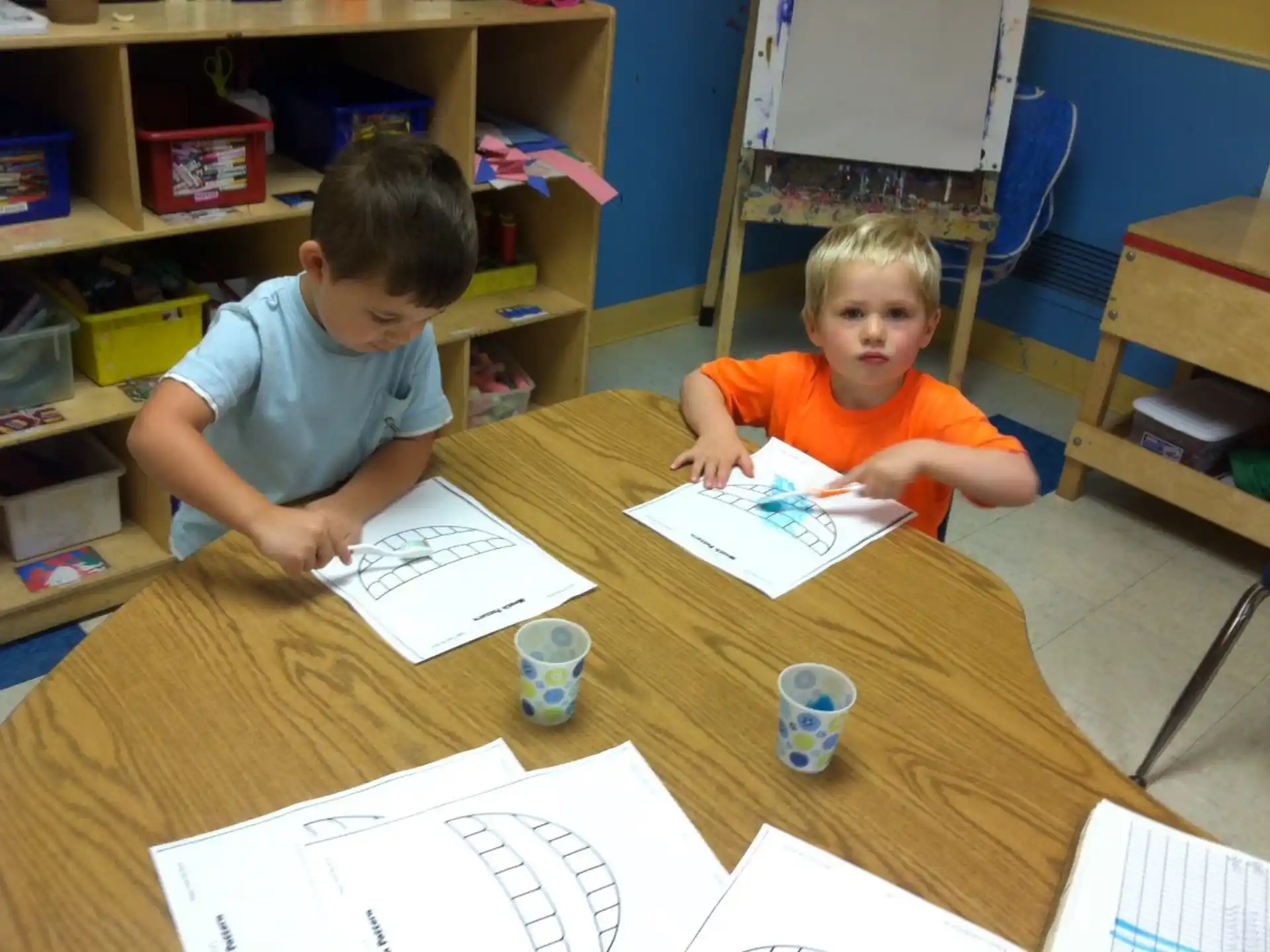a couple of boys sitting at a table looking at papers