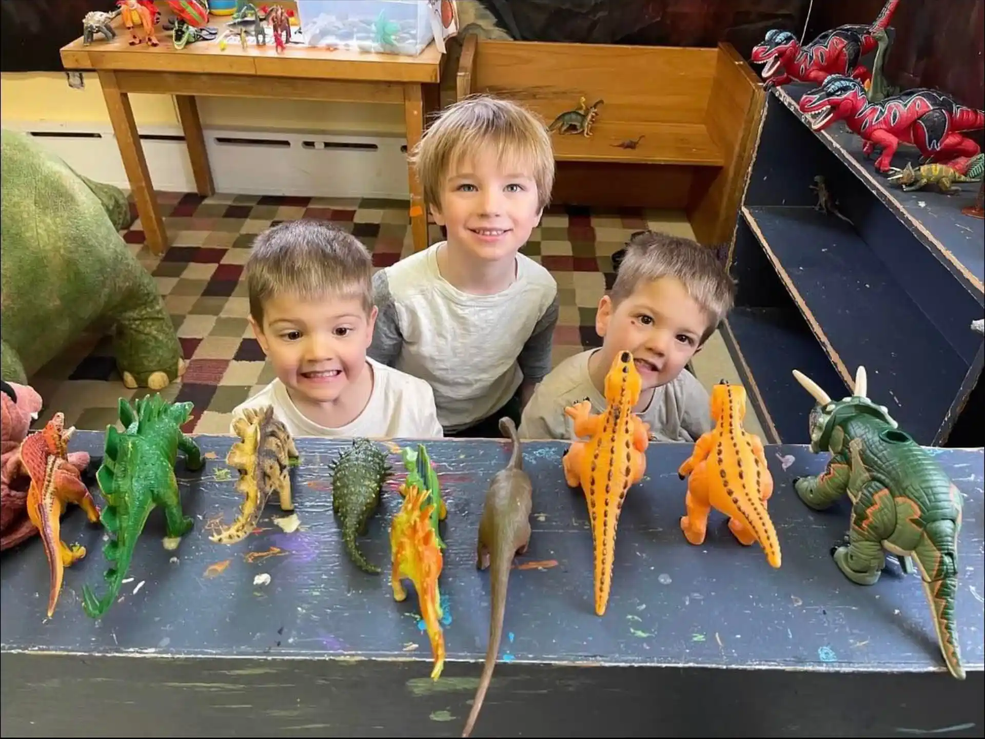a group of kids sitting on a table with toys