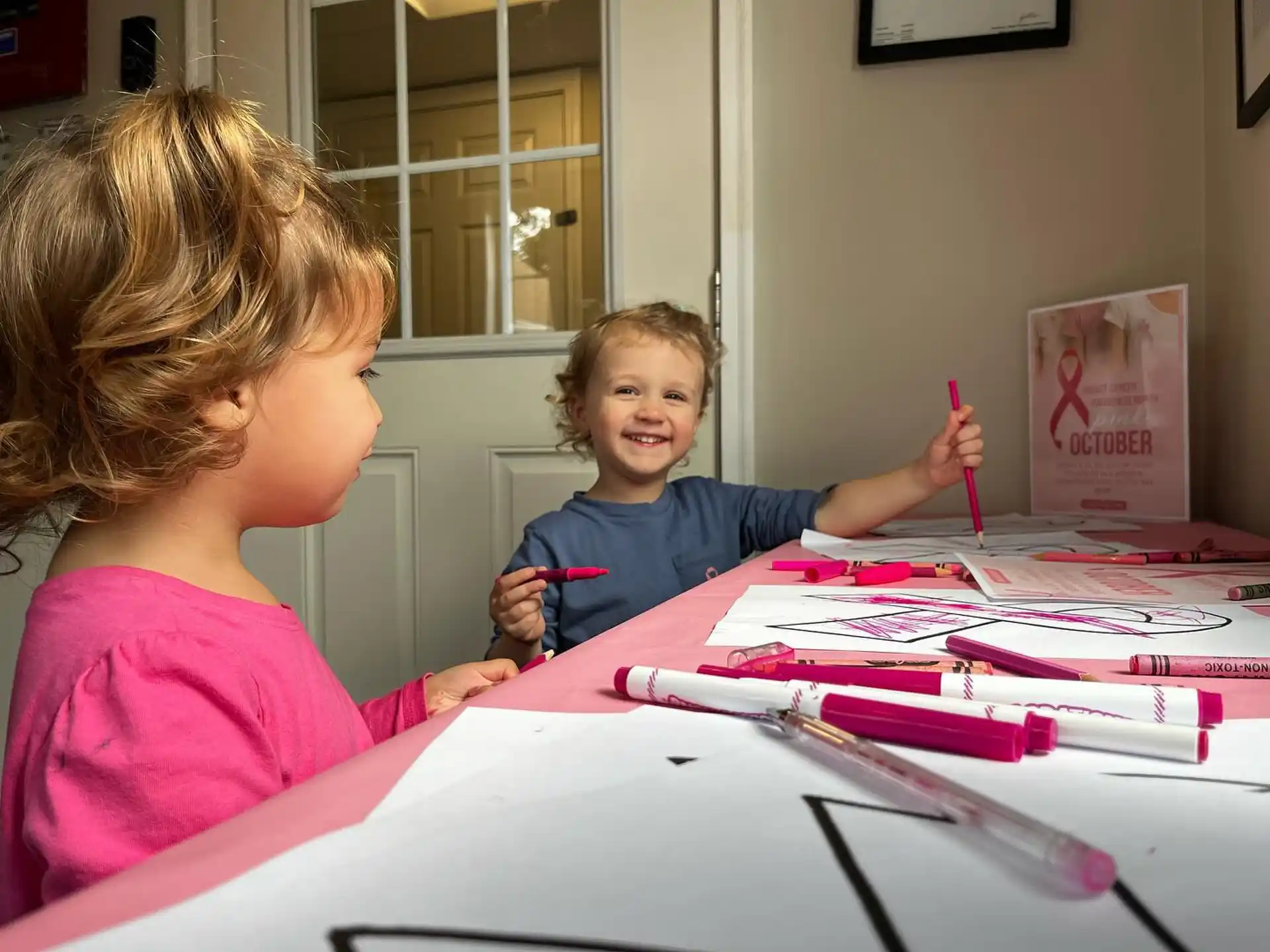 a person and a child sitting at a table with colored pencils