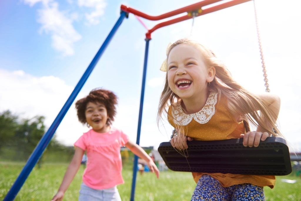 a couple of girls playing on a swing set