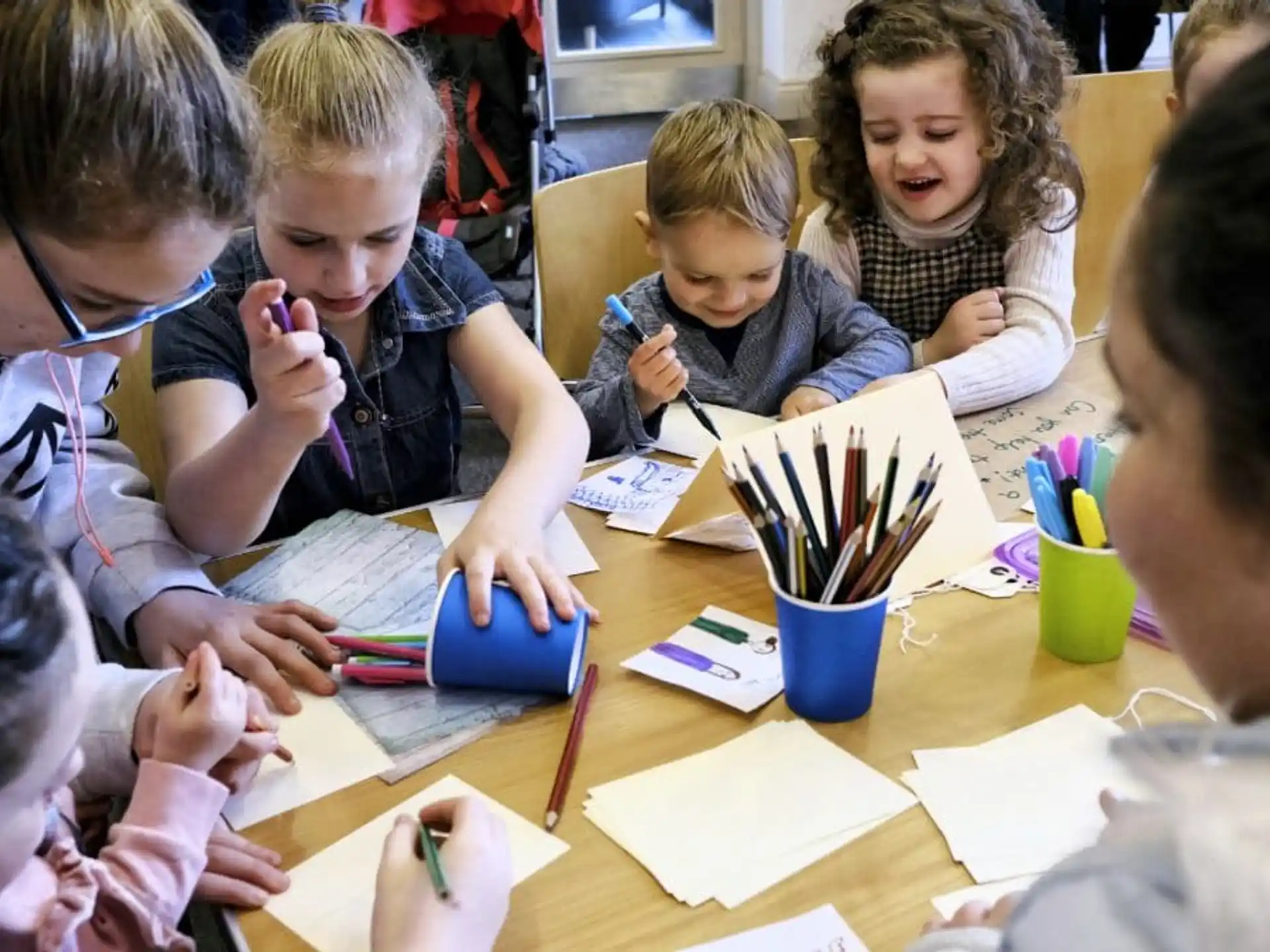 a group of children sitting at a table writing on paper