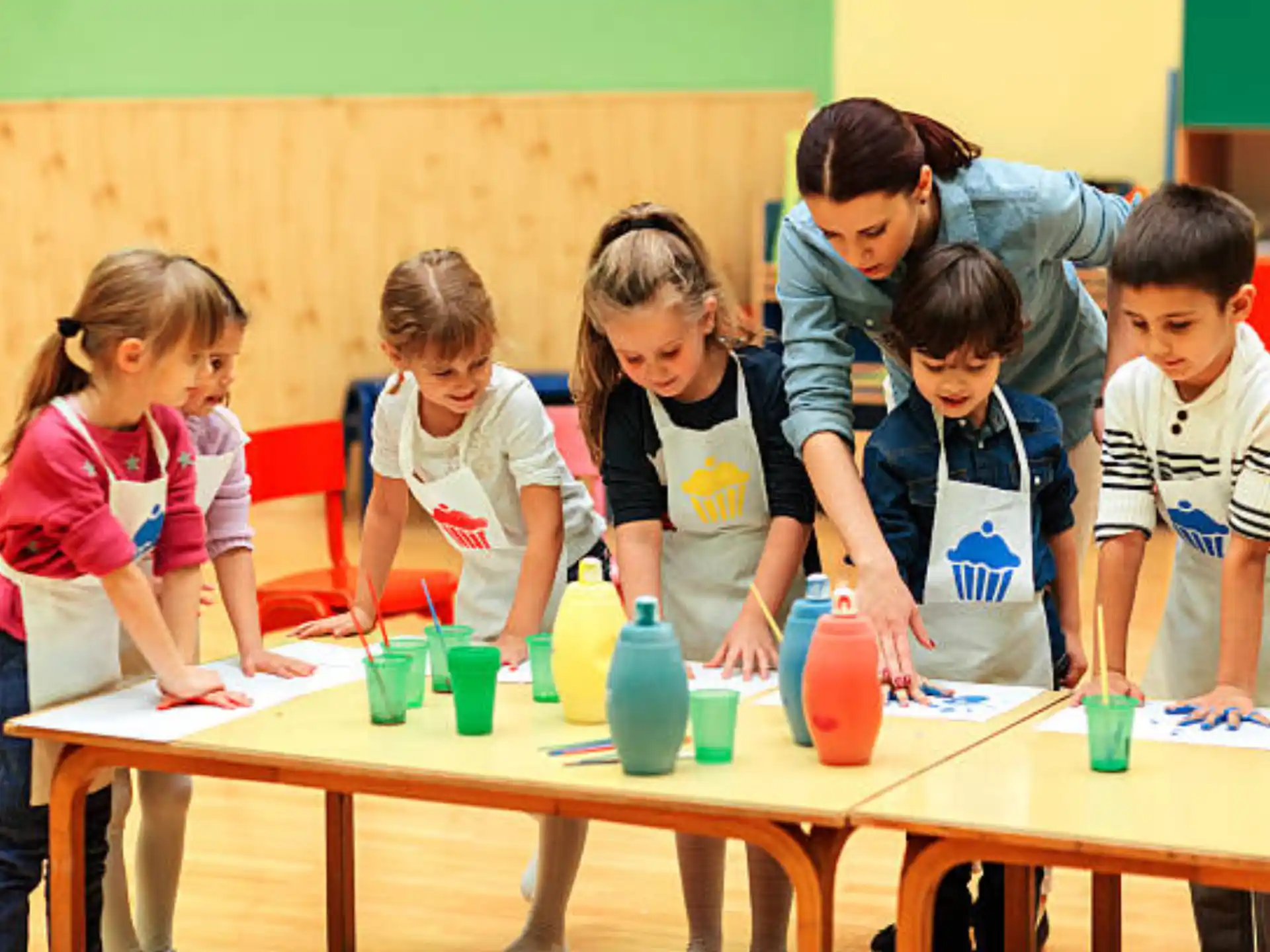 a group of children standing around a table with cups on it
