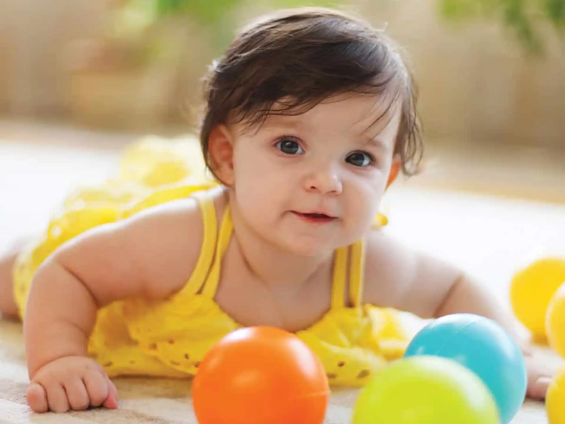 a baby lying on the ground with balls around it