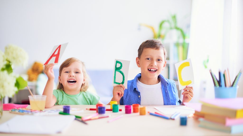 a couple of kids holding up a green sign with colorful paper on it