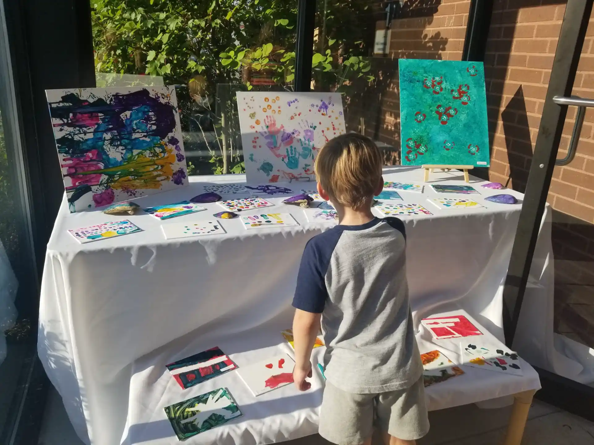 a child standing next to a table with art on it