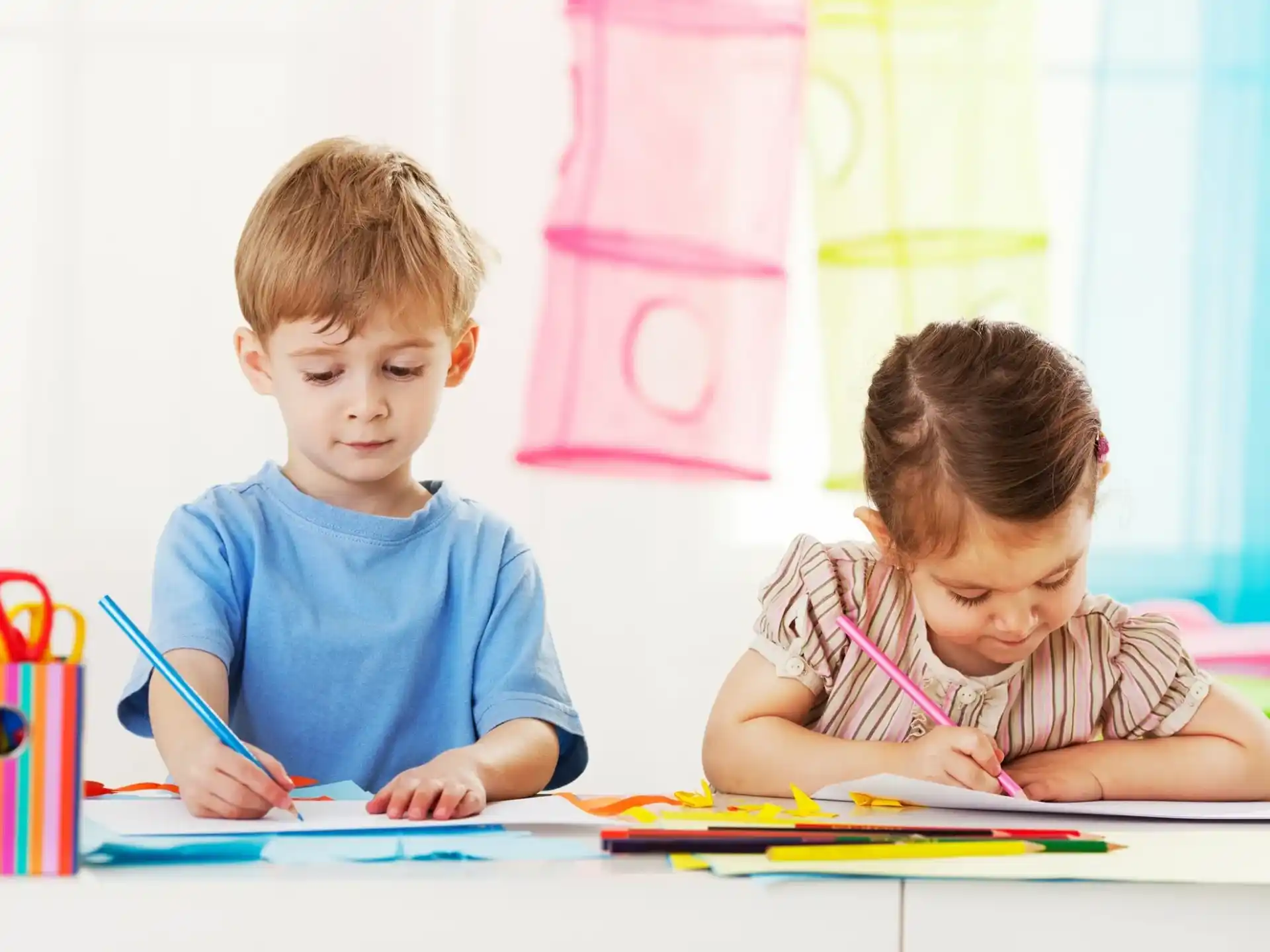 a couple of kids sitting at a table looking at a book