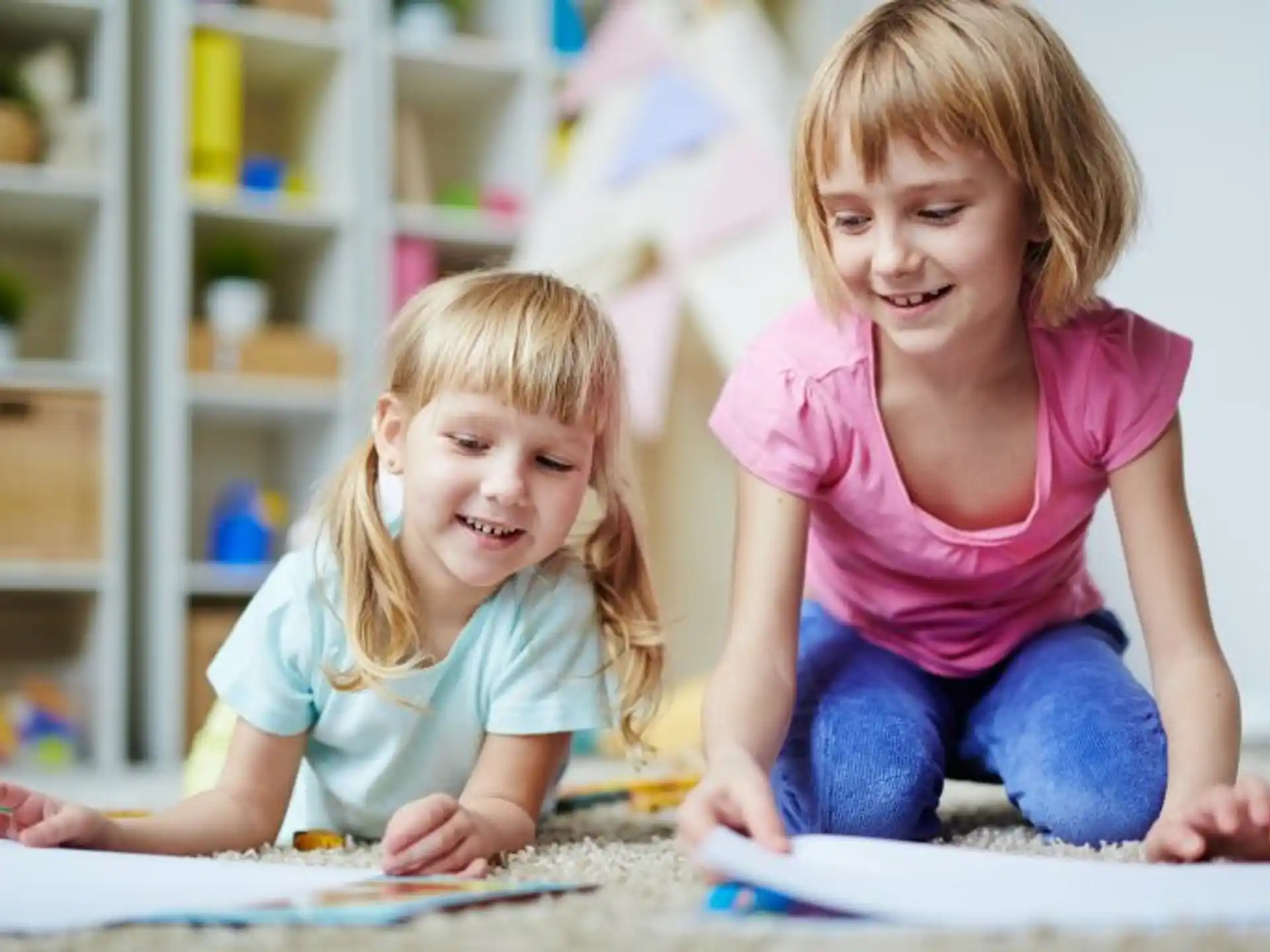 a couple of young girls sitting on the floor