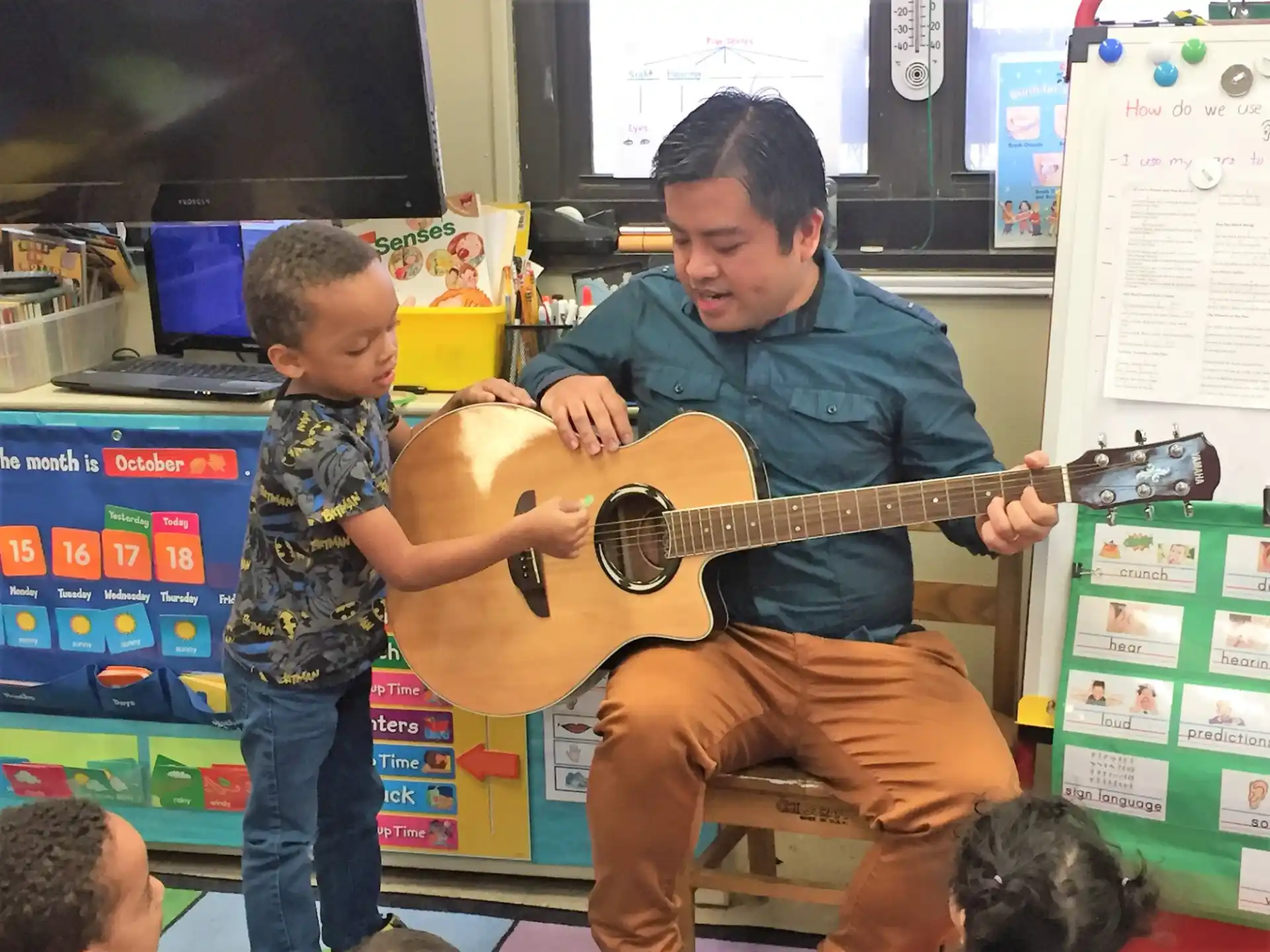 a person playing a guitar with a boy watching