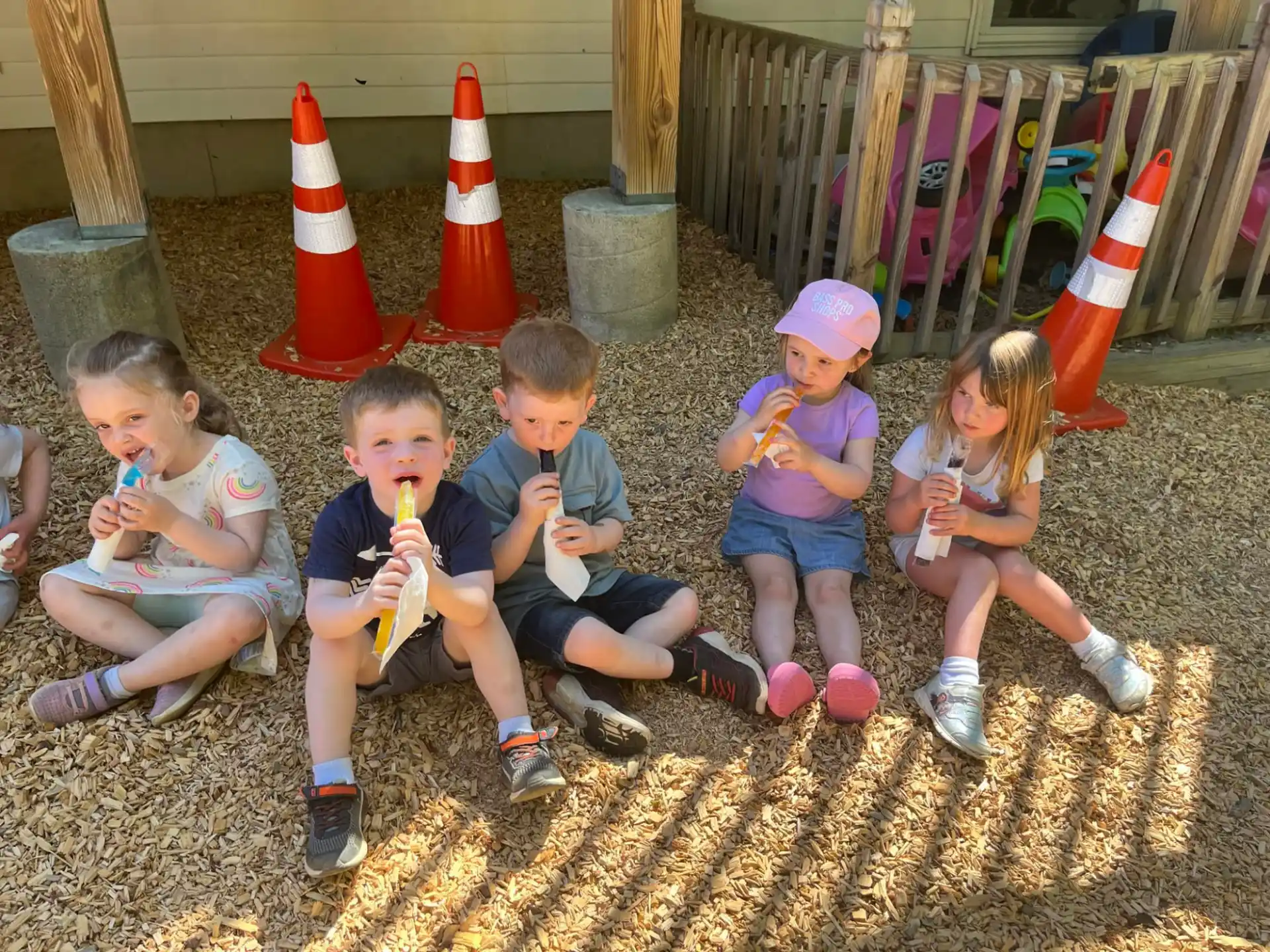 a group of kids sitting on the ground eating ice cream cones