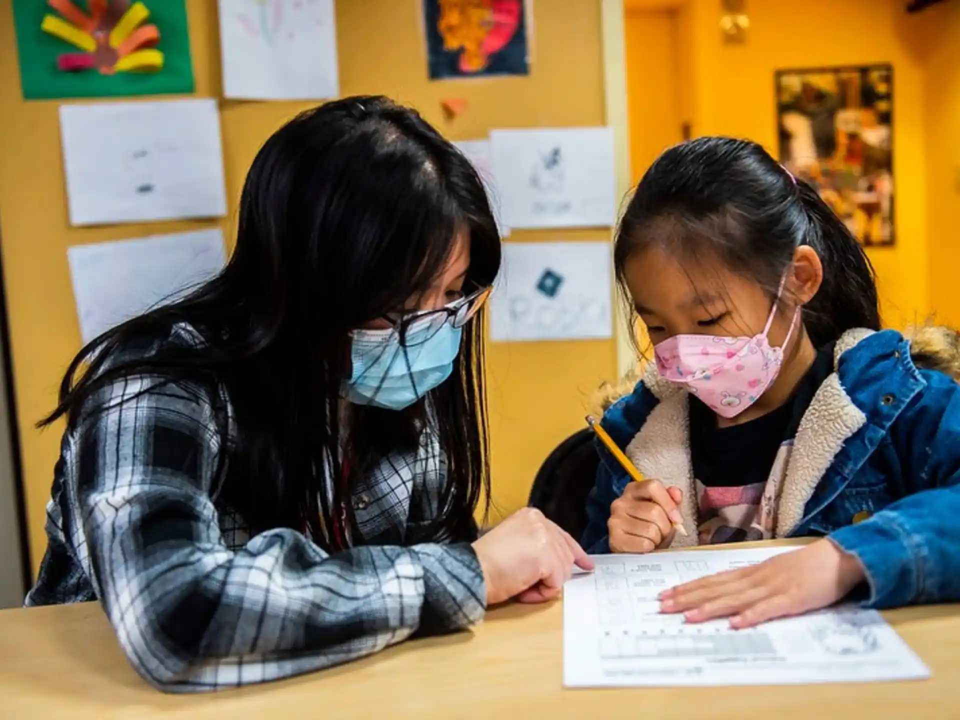 a couple of young girls wearing safety goggles and looking at a piece of paper