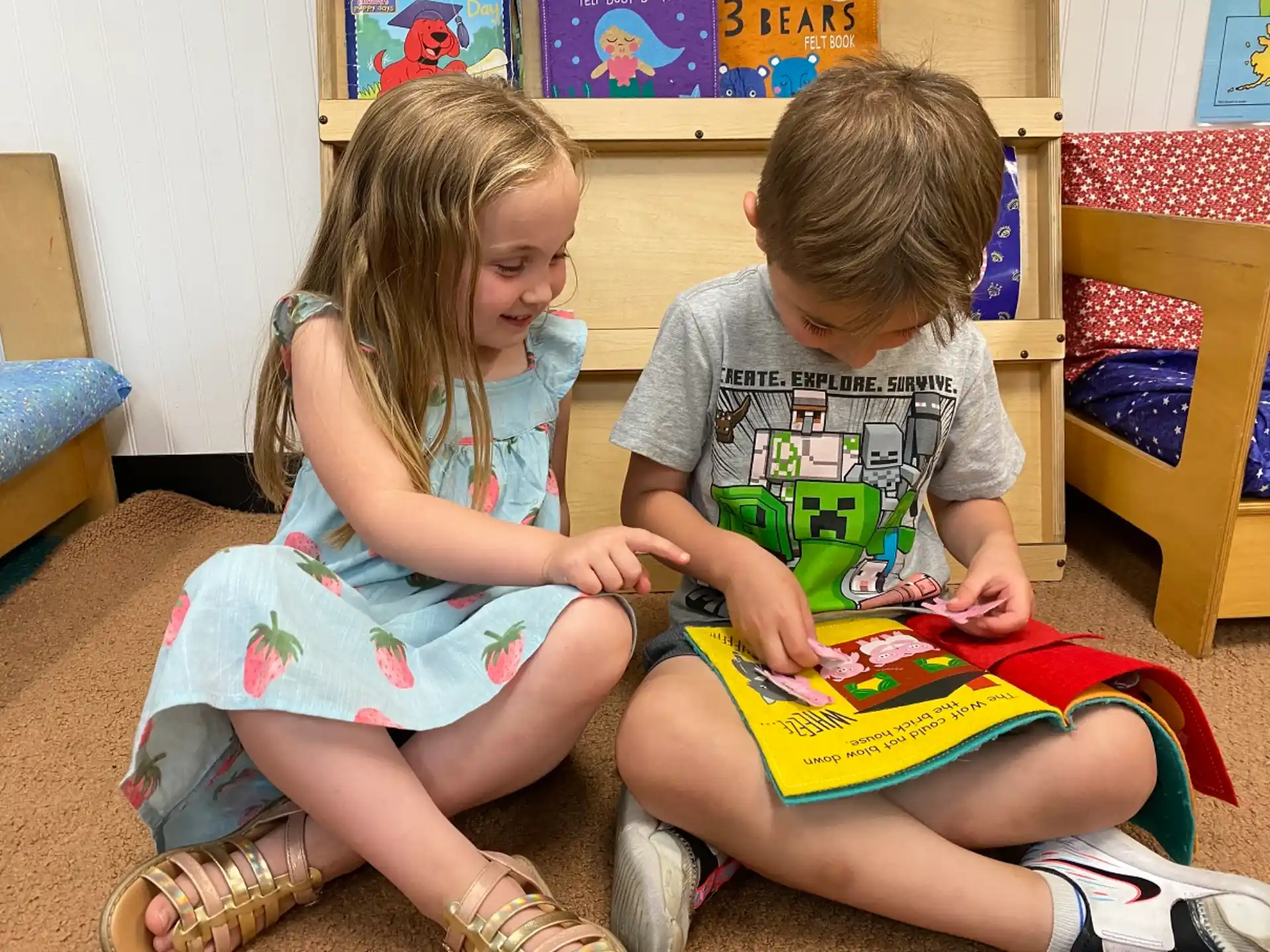 a couple of children sitting on the floor reading a book