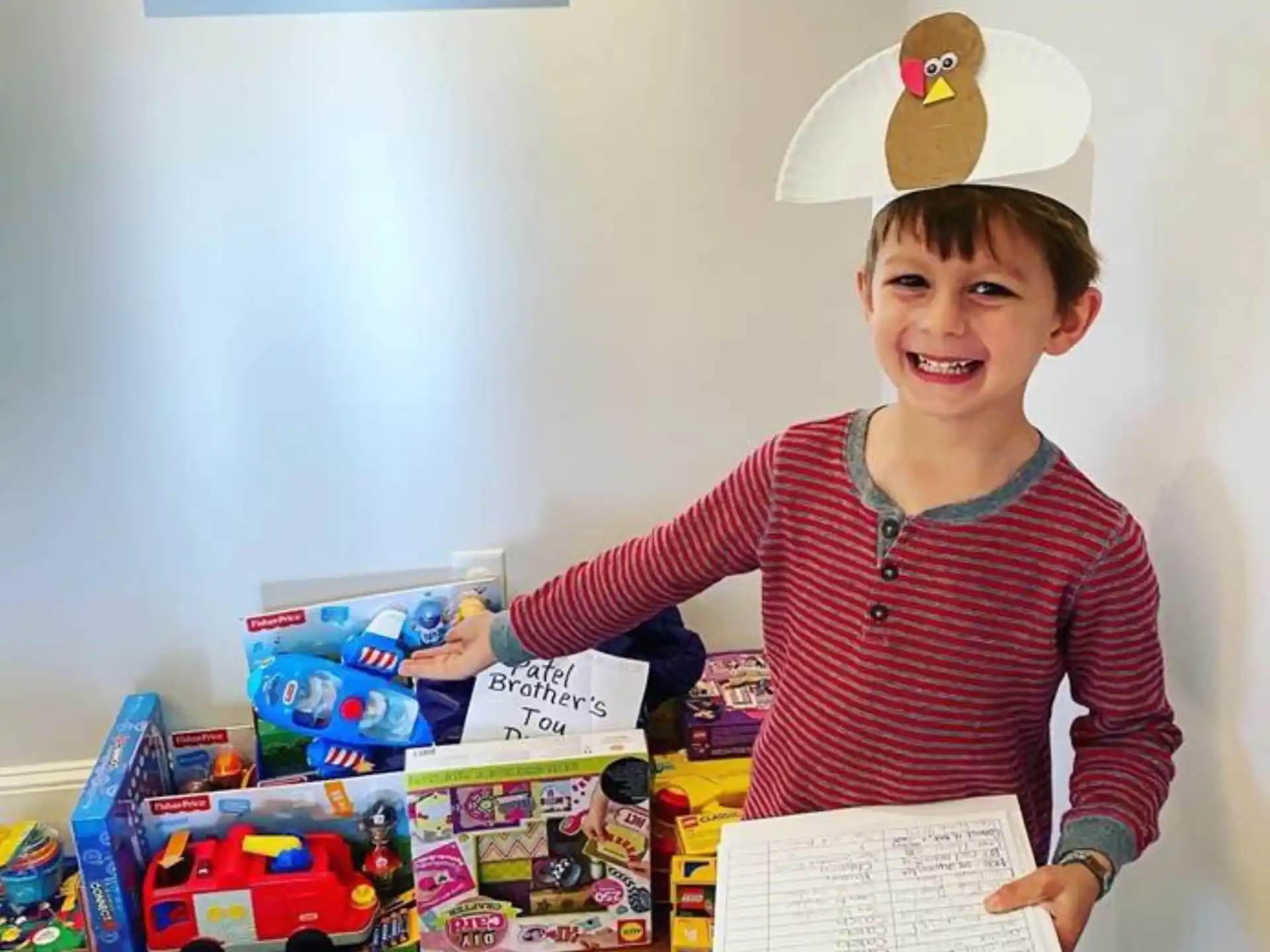 a boy holding a paper and a stack of toys