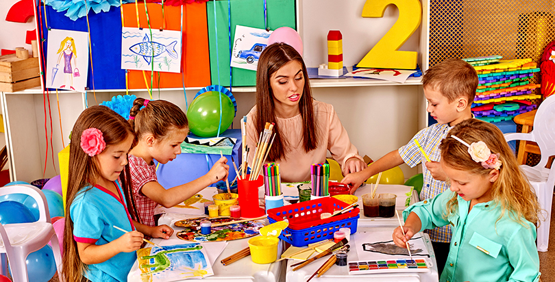 a woman and several children painting