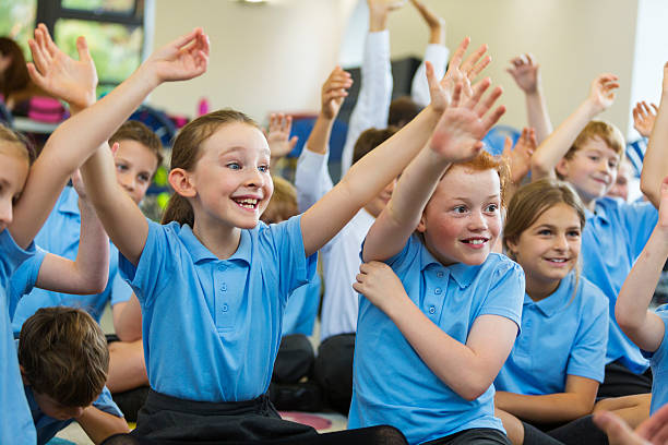a group of children raising their hands