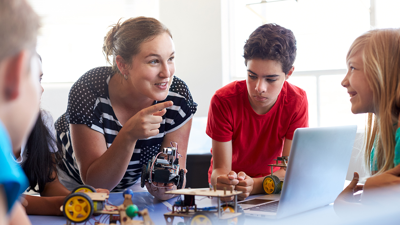 a group of people sitting around a table looking at a laptop