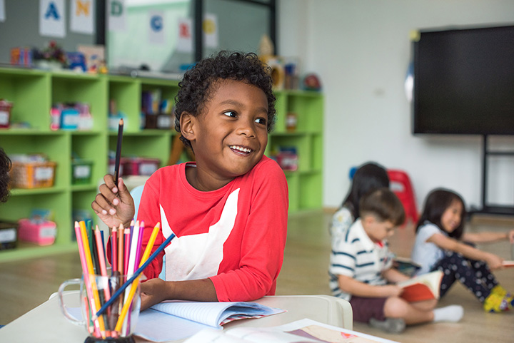 a young boy holding a pencil