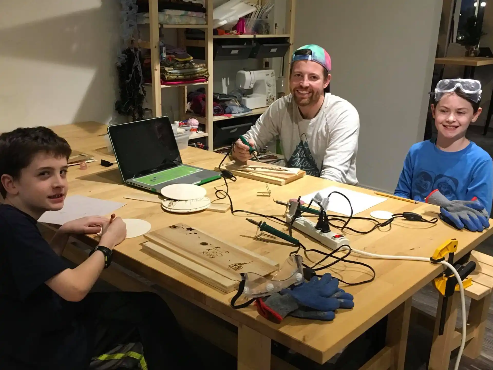 a group of people sitting at a table with a laptop and wires