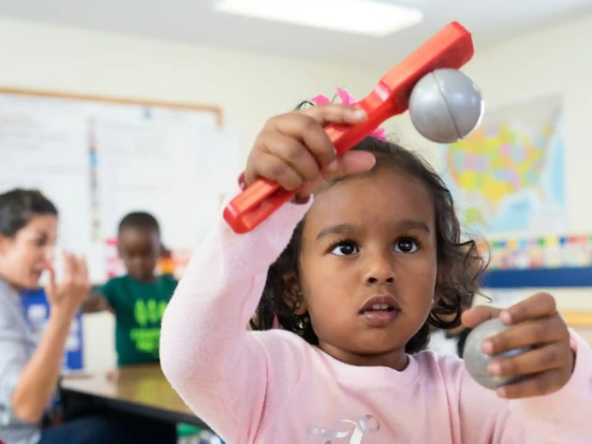 a young girl holding a red toy