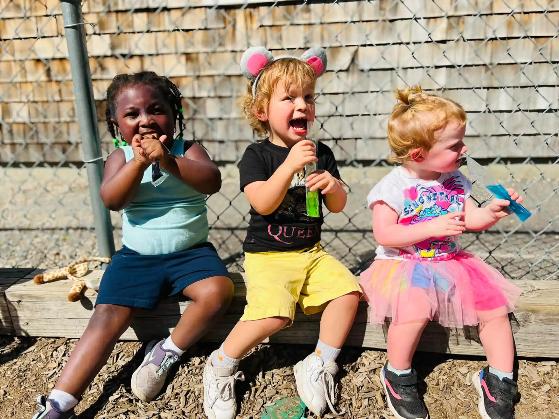 a group of kids sitting on the ground with their mouths open