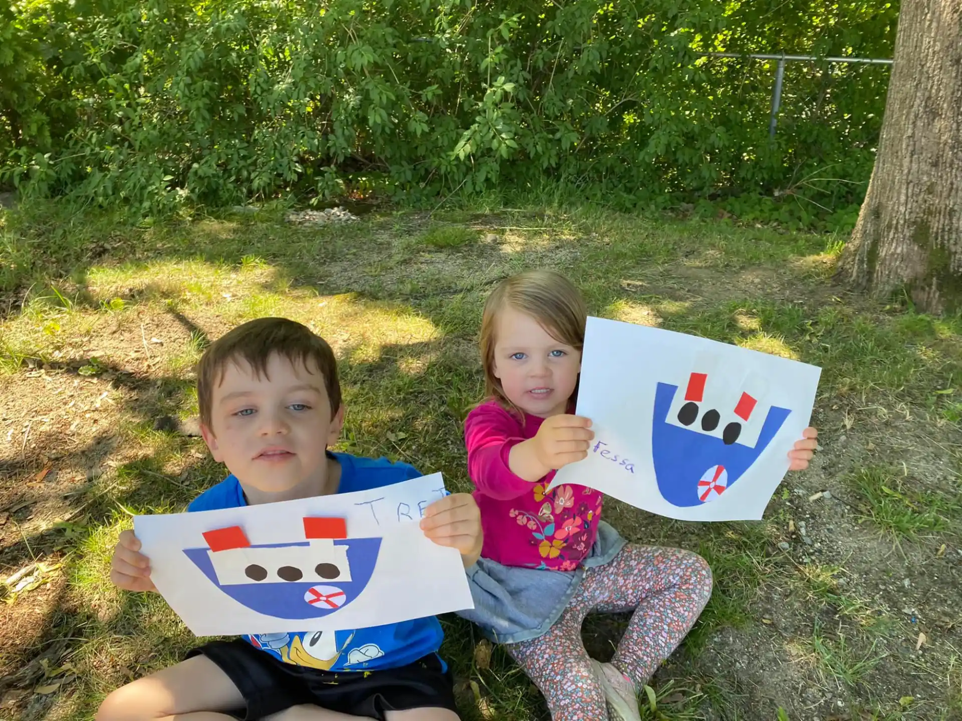 a couple of kids sitting on the ground holding a kite