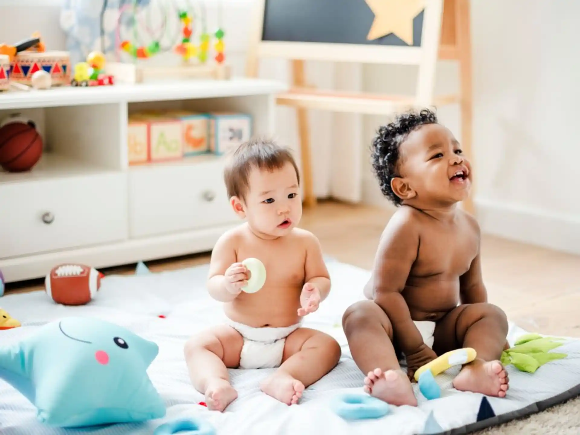 two babies sitting on a bed
