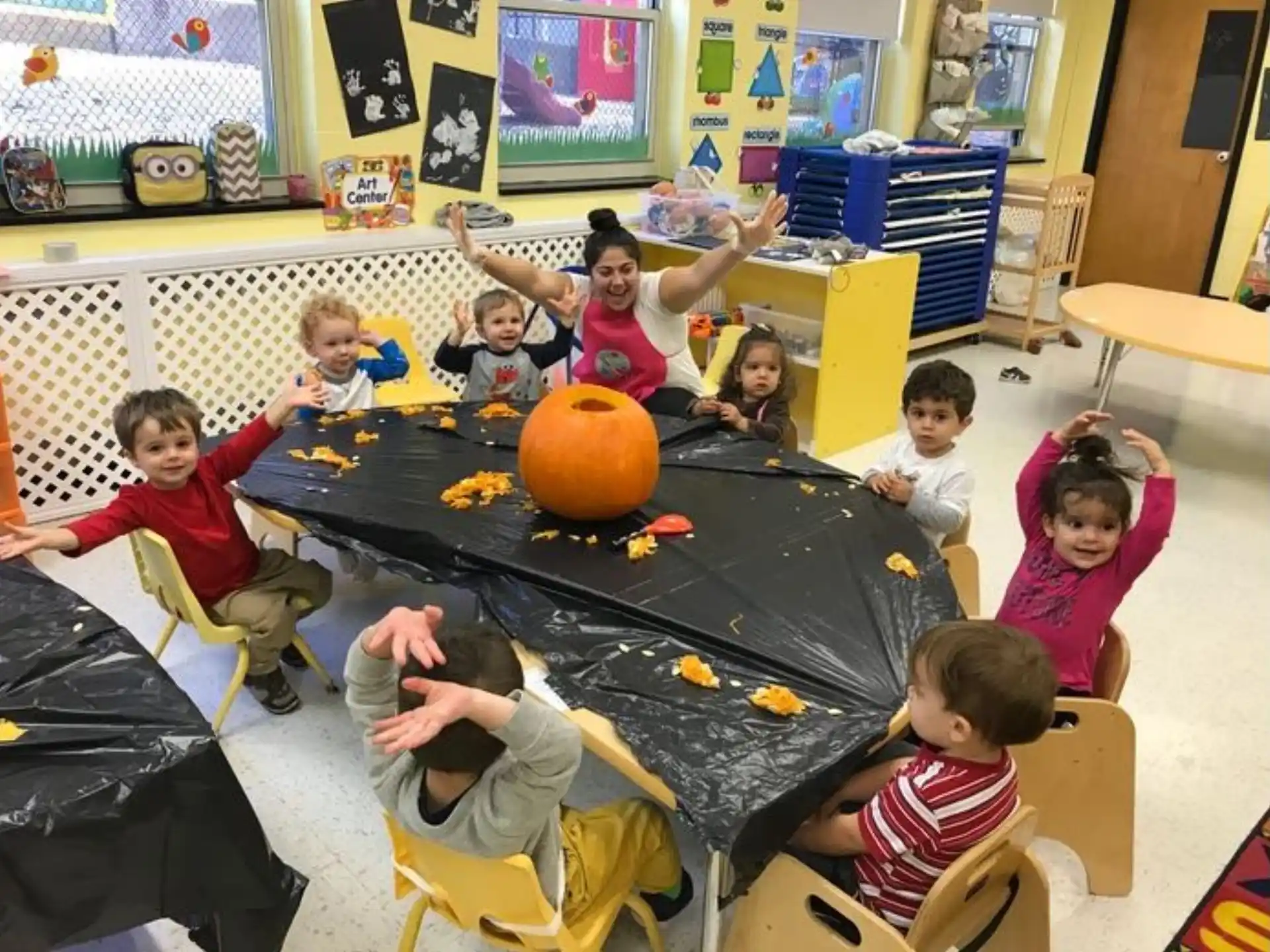 a group of children sitting around a table with a pumpkin
