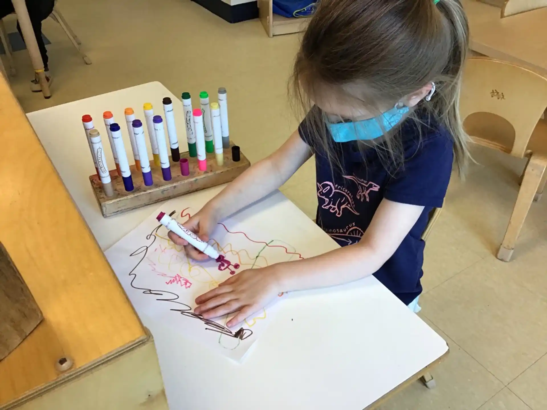 a girl drawing on a white paper