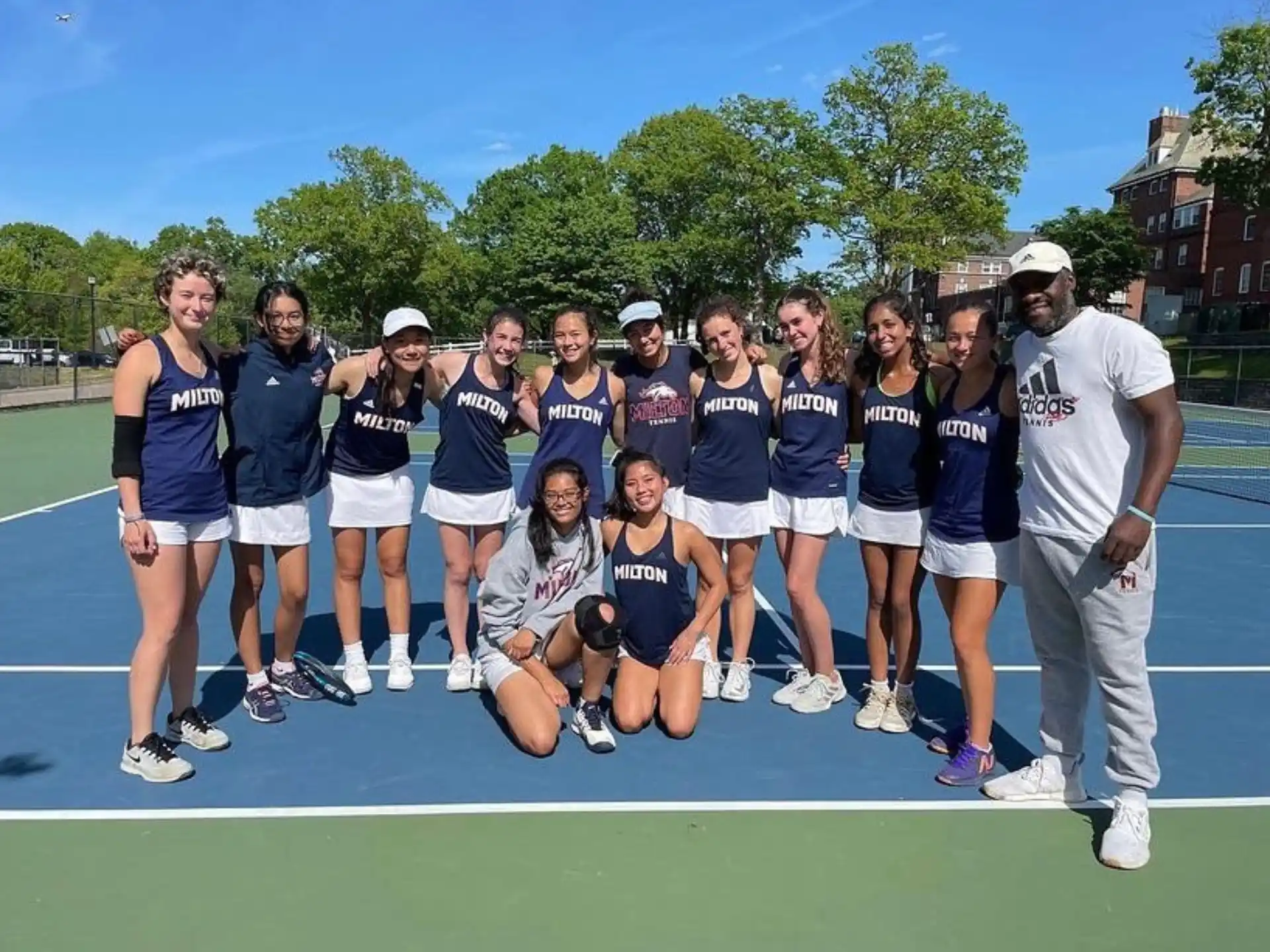 a group of people posing for a photo on a tennis court