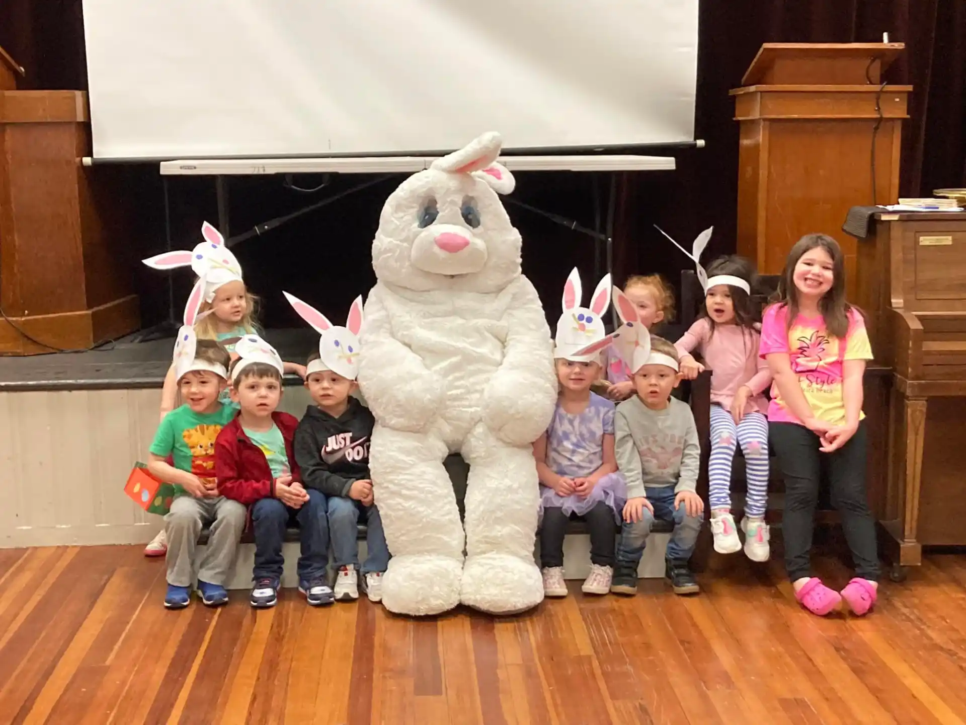 a group of children posing with a person in a rabbit garment
