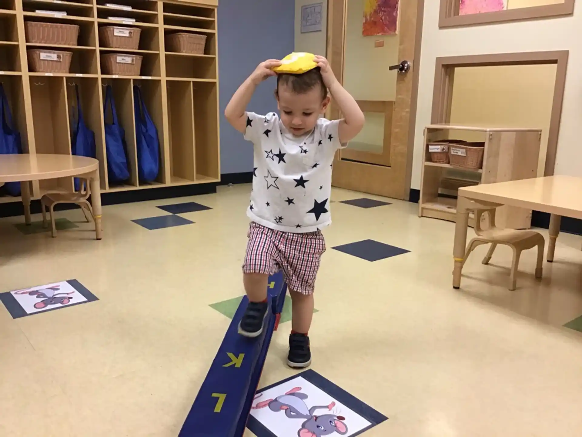 a child holding a yellow object in a room with books on the floor