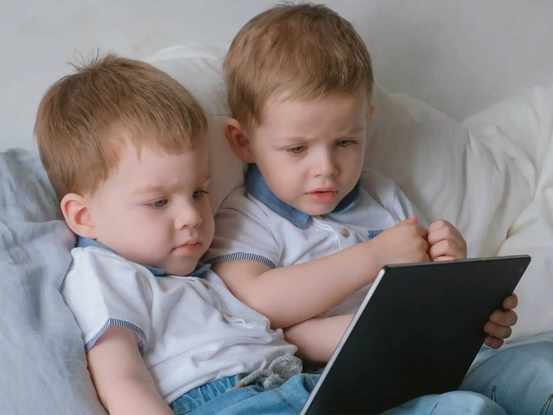 a couple of young boys looking at a tablet