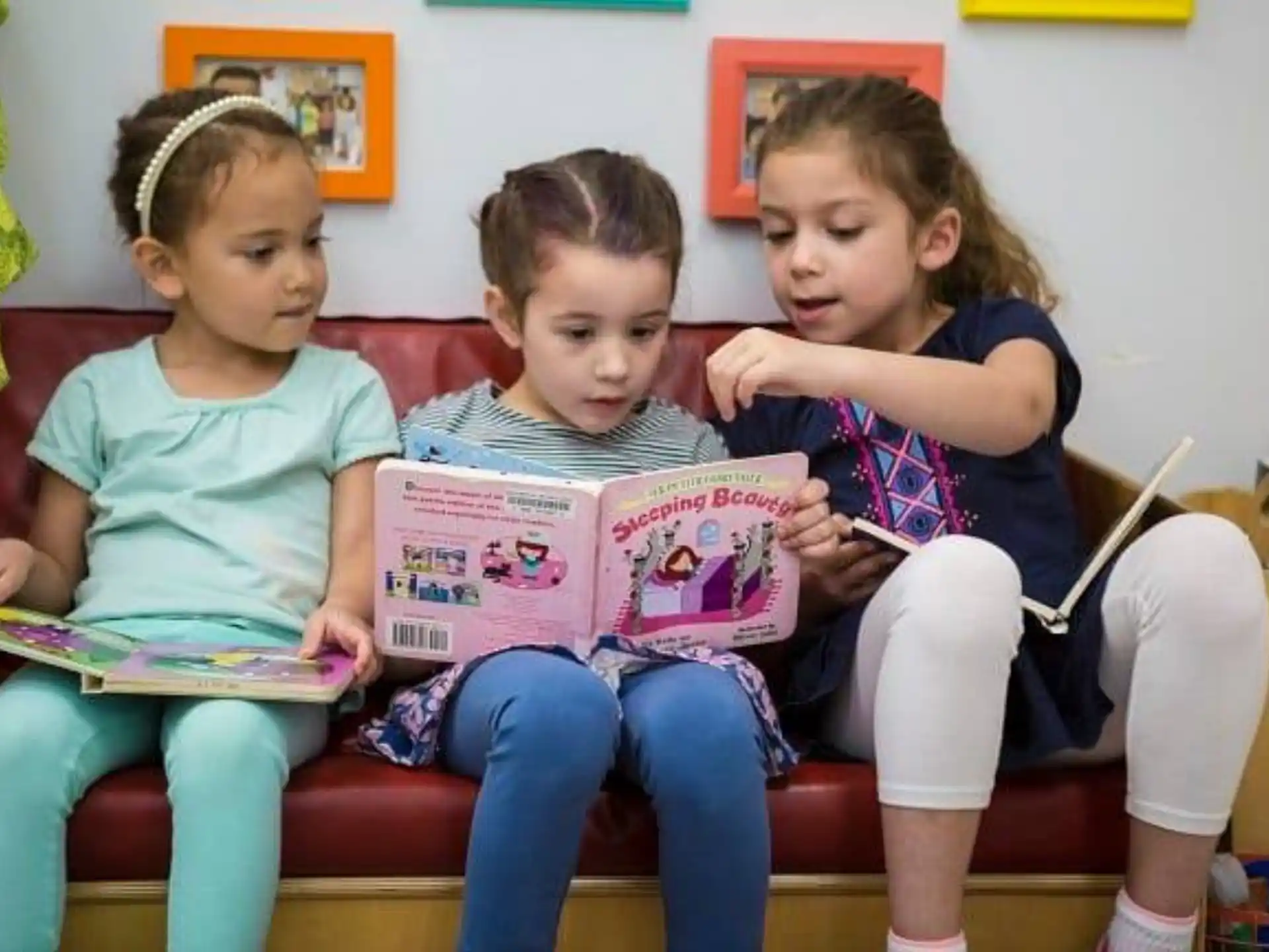 a group of children sitting on a bench reading books
