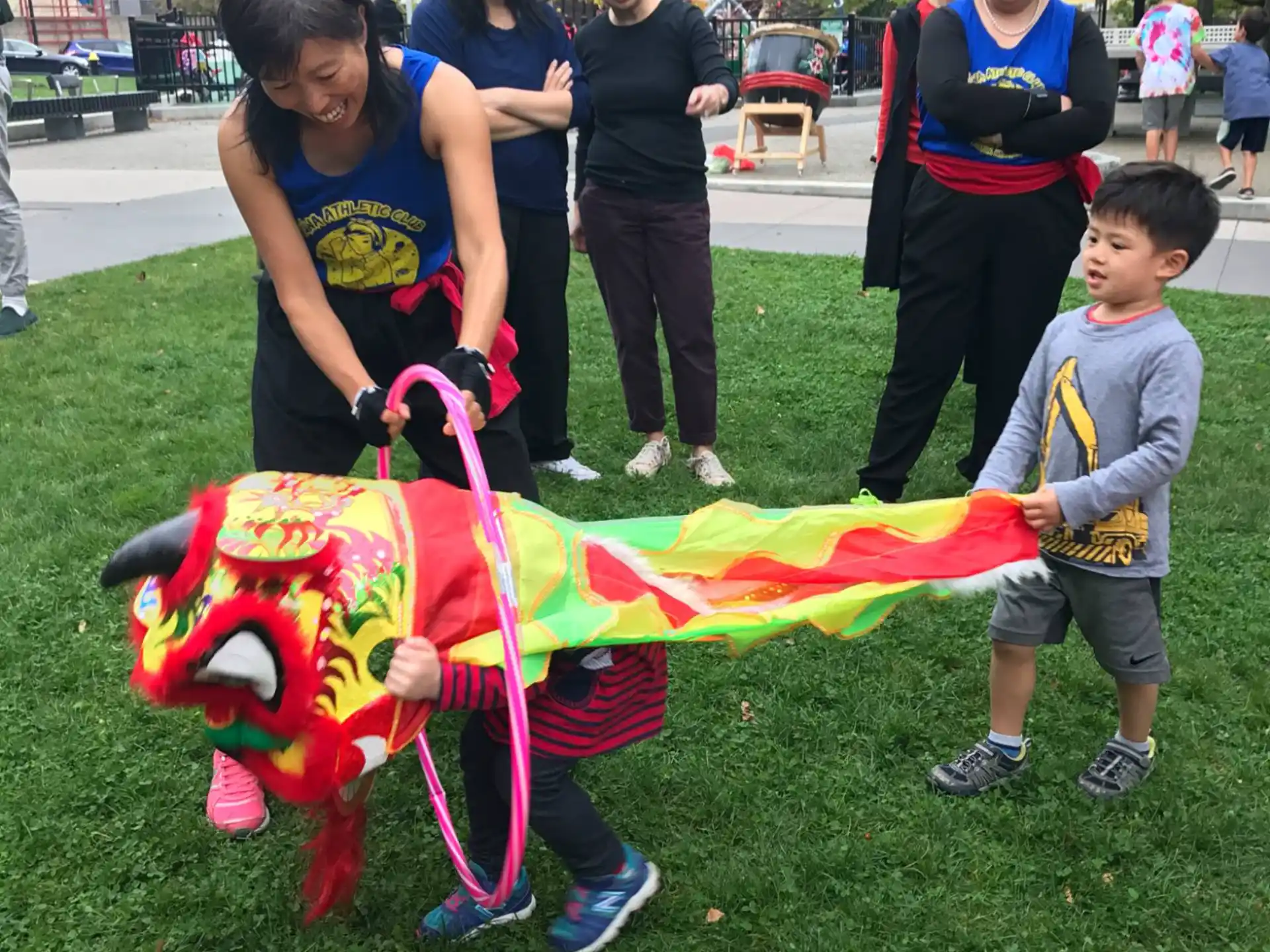 a group of people standing on grass holding a kite
