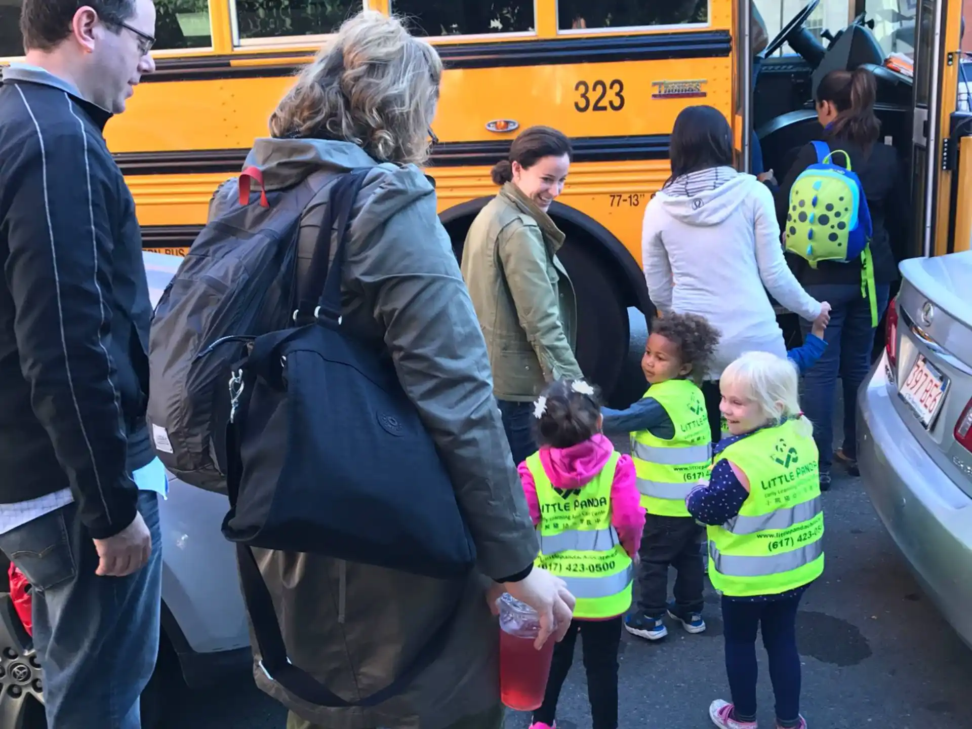 a group of people standing outside of a yellow bus