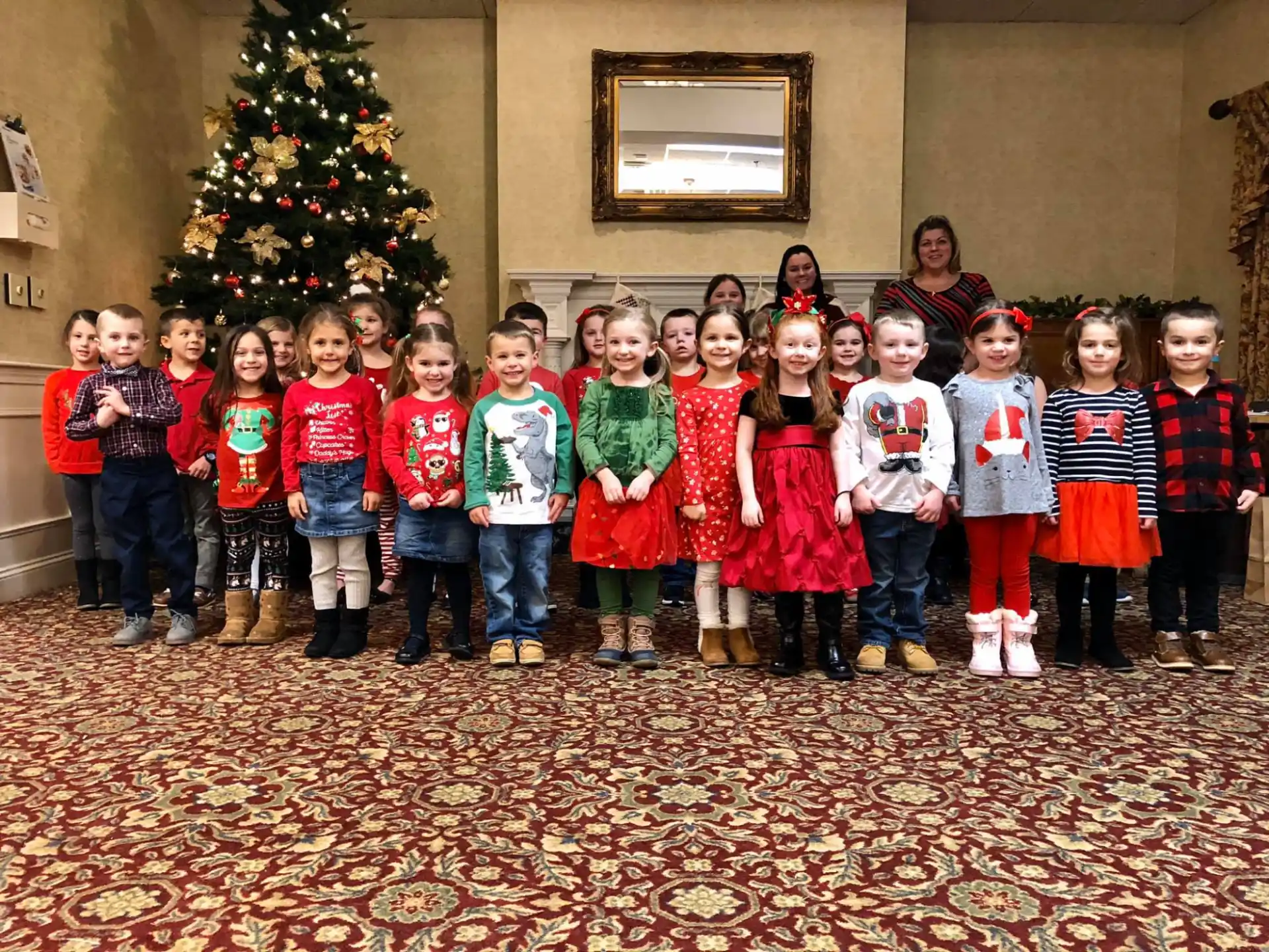 a group of children posing for a photo in front of a christmas tree