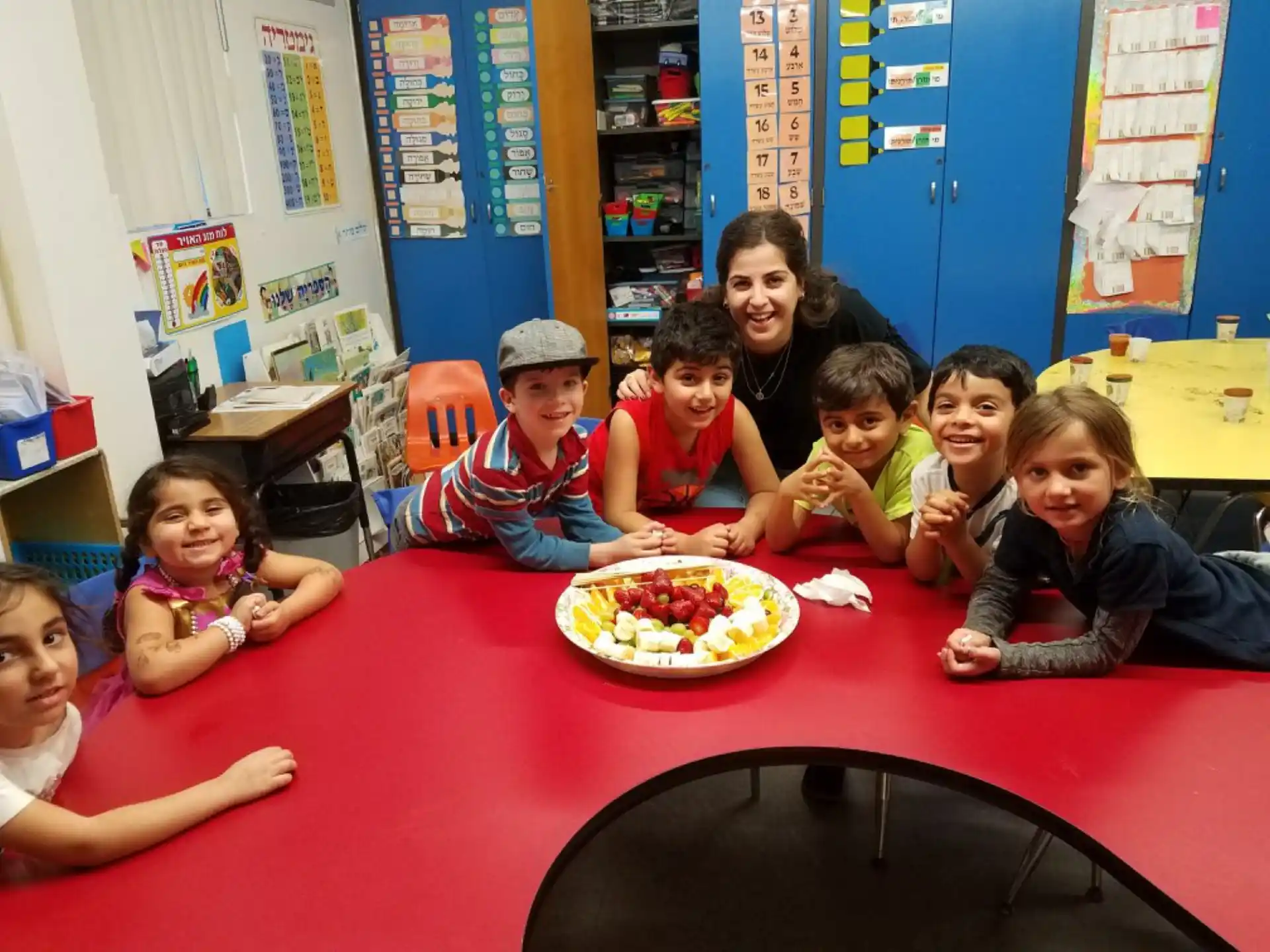 a group of children sitting at a table with a pizza