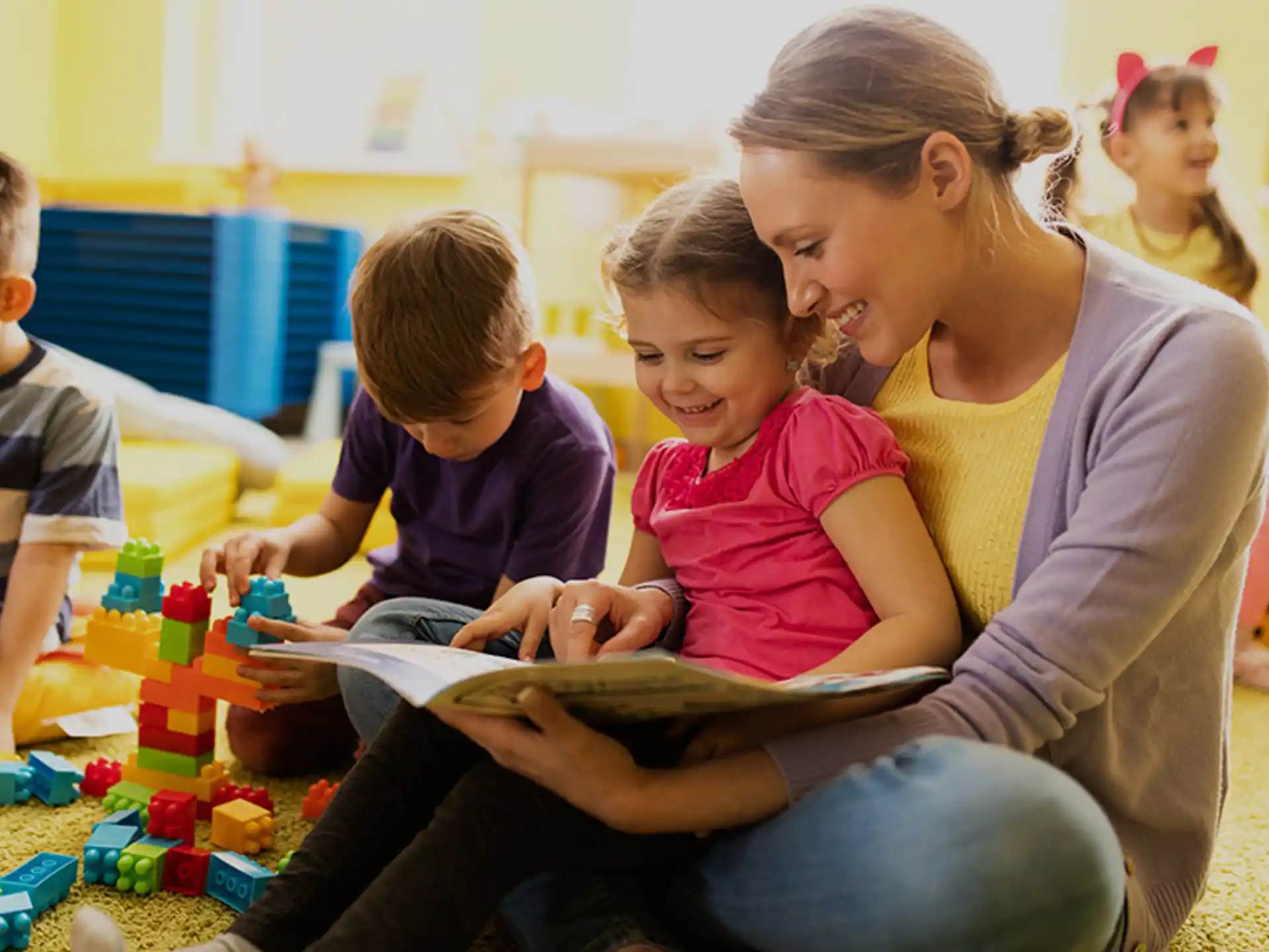 a woman reading a book to a group of children