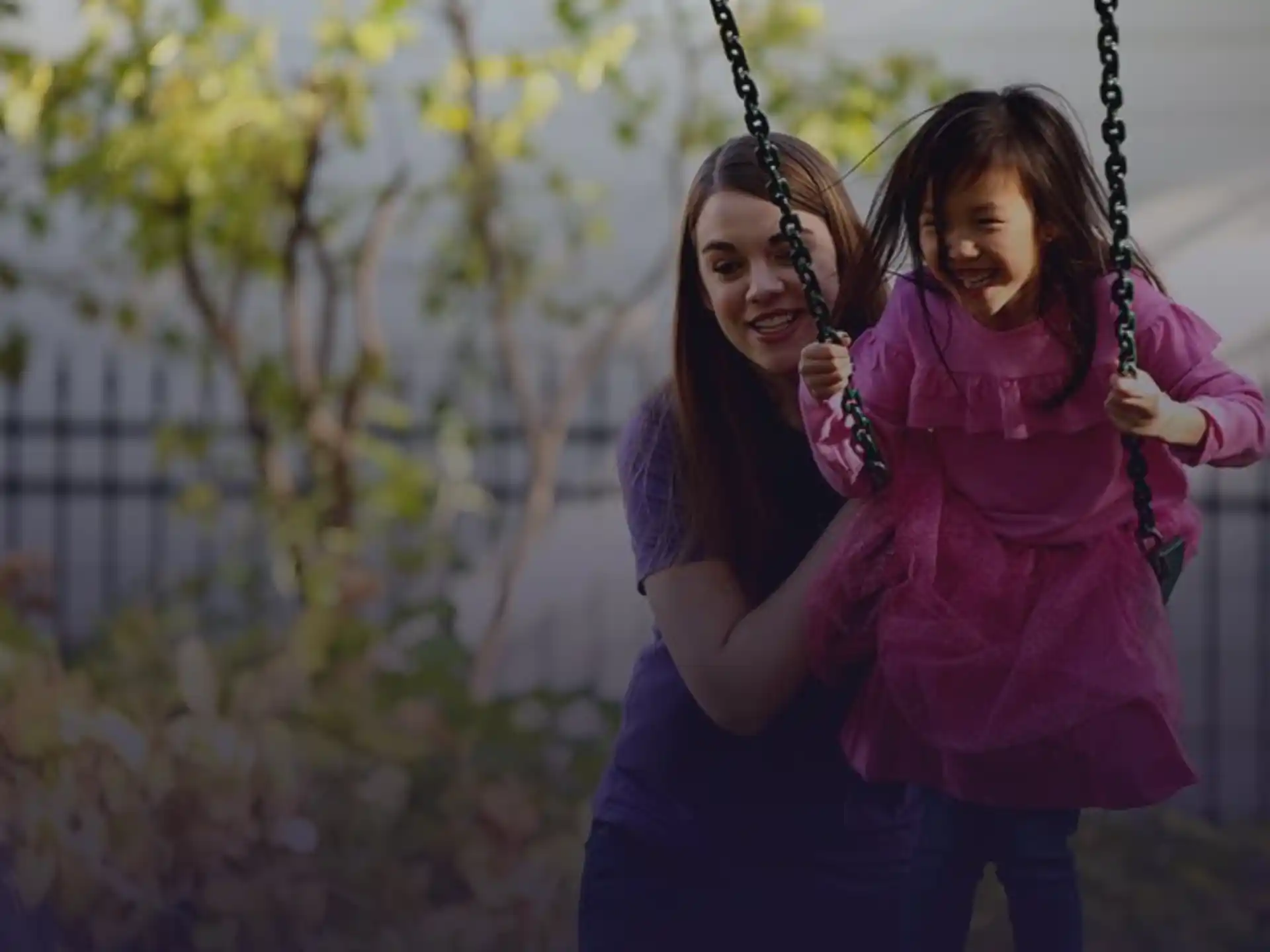 a person holding a girl on a swing