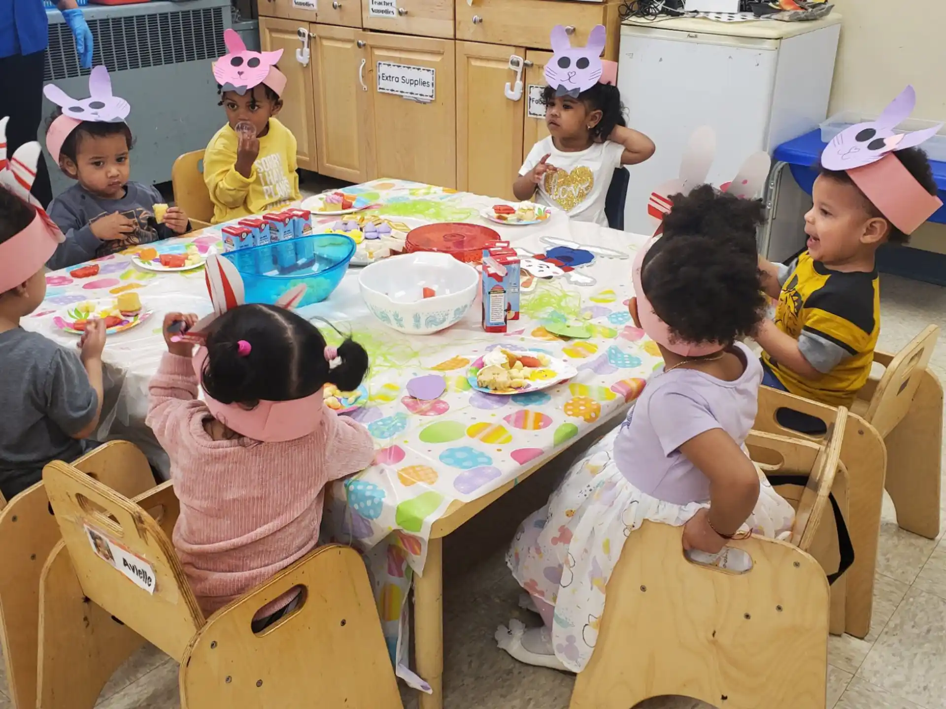 a group of children sitting around a table with food on it