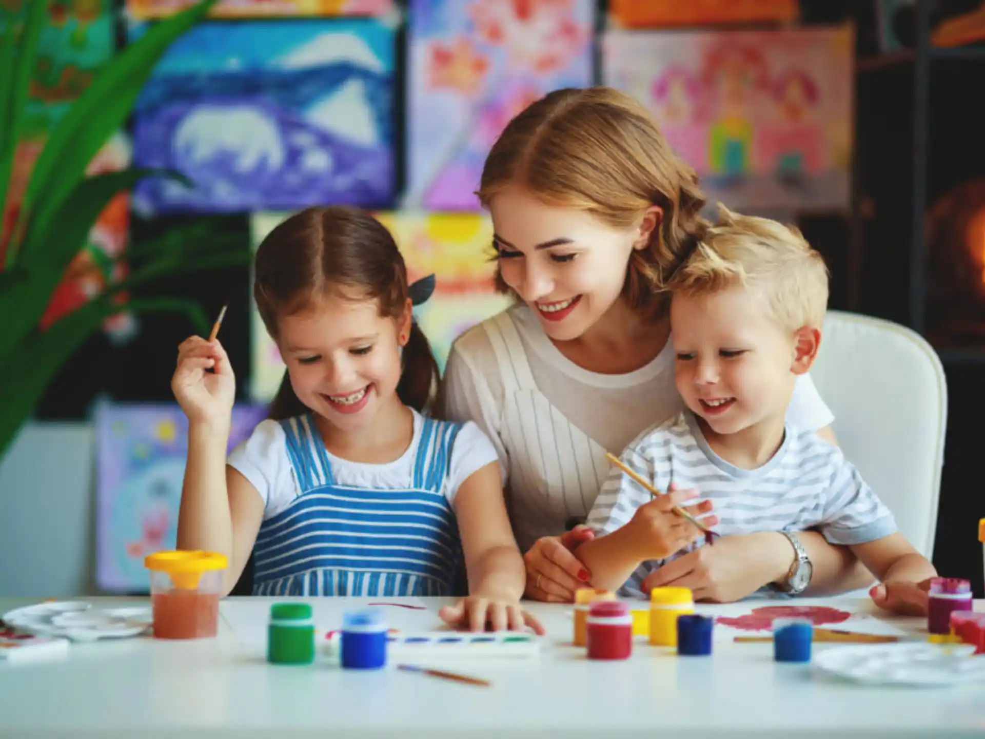a group of children sitting at a table with cups and a plant