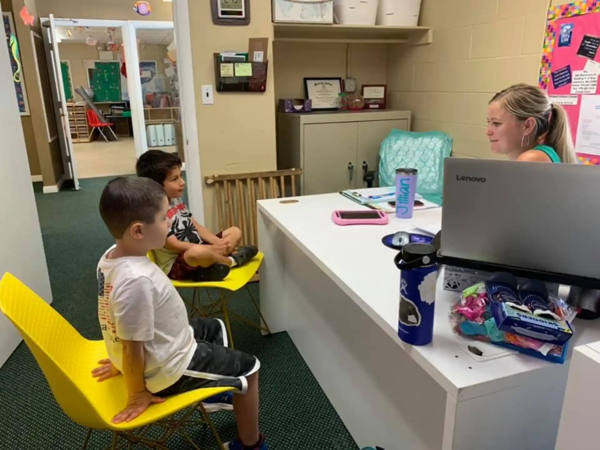 a person and a child sitting at a table with a laptop