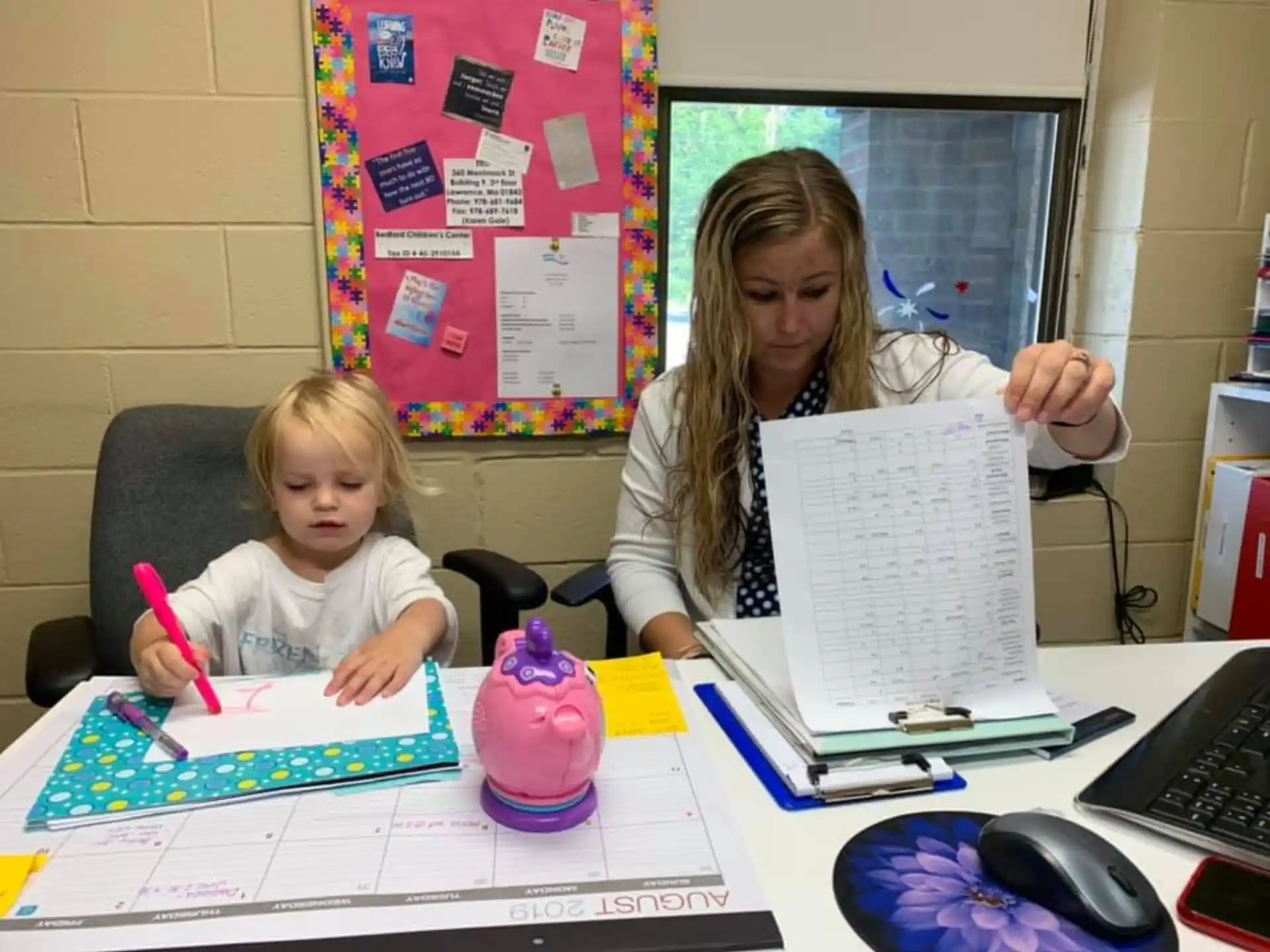 a person and a child sitting at a table with a paper