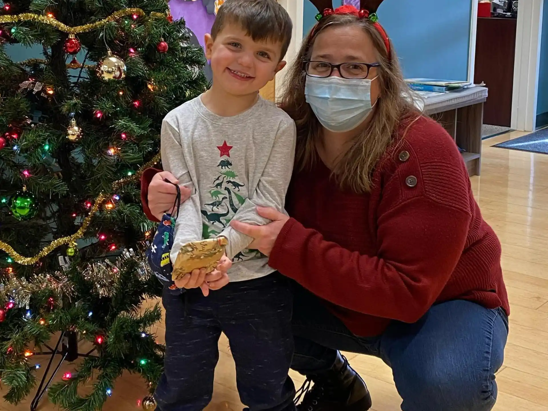 a person and a boy posing for a picture next to a christmas tree